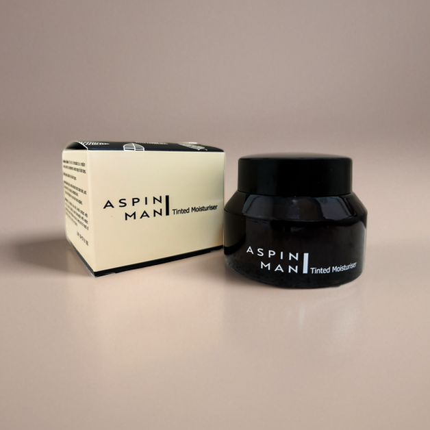 Aspin Man Tinted Moisturizer jar next to its sleek, black and white packaging, emphasizing the brand’s minimalist design.